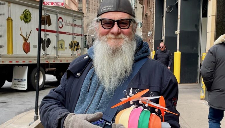 Charlie Wheeler, manufacturer of propeller beanies, walks the streets of Chicago hawking his wares.